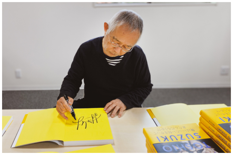 「ALL ABOUT TOSHIO SUZUKI」にサインをする鈴木敏夫